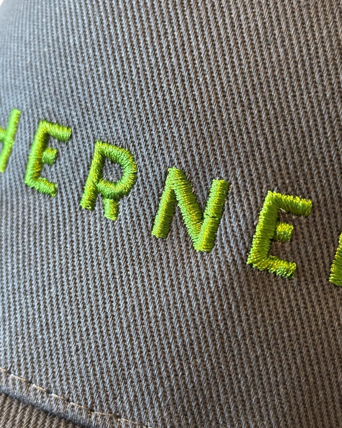 Close up of the front stitching detail on a dark dad cap with Northerner embroidery / embroidered slogan logo. Hat for men and women - unisex. Great gift for someone from Yorkshire or Lancashire.