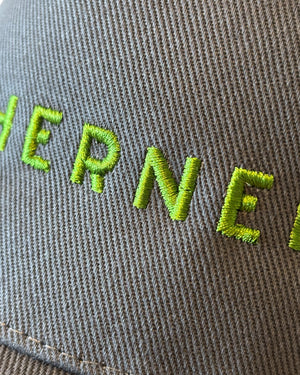 Close up of the front stitching detail on a dark charcoal grey dad cap with olive khaki green Northerner embroidery / embroidered slogan logo. Hat for men and women - unisex. Great gift for someone from Yorkshire or Lancashire. 