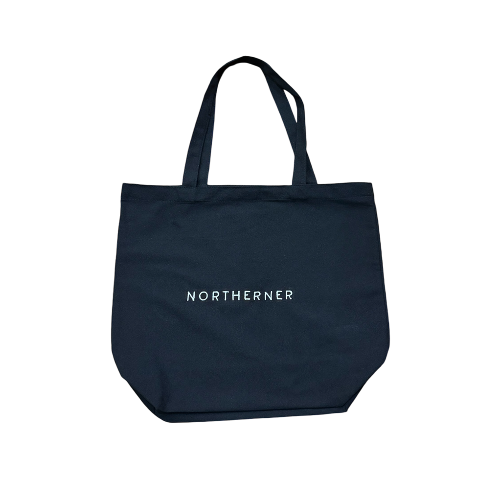 Cotton canvas tote shoulder bag - perfect eco conscious shopping bag / bag for life. Great gift for Northerners and people from Yorkshire of Lancashire. bag with embroidered Northerner slogan in bold, minimalist font. Bag shown laying flat on the ground with a background. Men's and ladies / women's bag