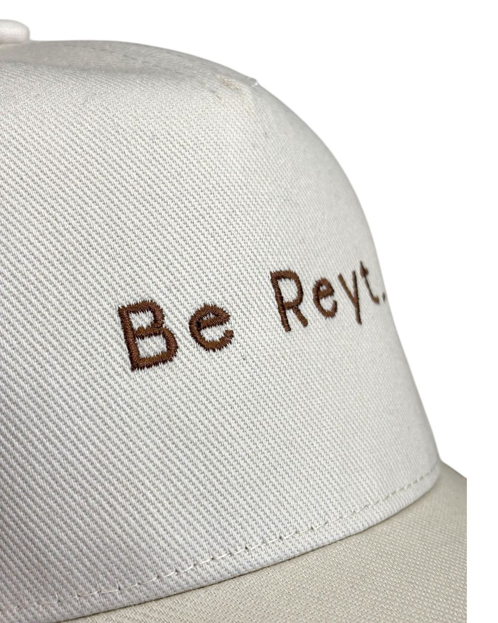 Close up front view of the stitching on a neutral dad cap with minimalist funny Yorkshire / Northern / Lancashire slogan / logo in coffee embroidery/ embroidered. This hat would be a perfect gift for a Northerner. Suitable for men and women, it's unisex and great quality. It'll be reyt Yorkshire dialect gift