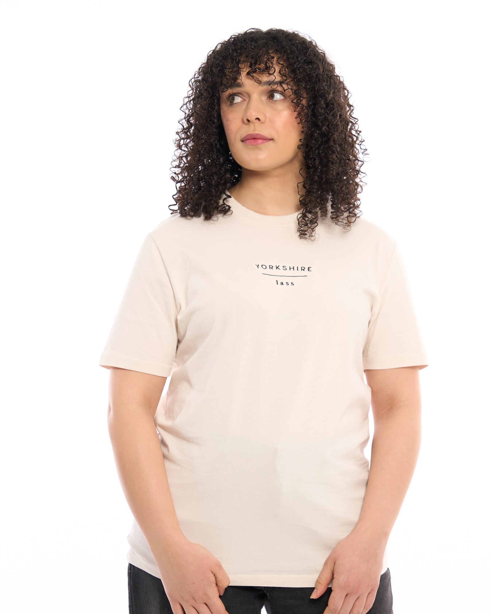 Female model wearing Yorkshire lass light cream white neutral t-shirt, with black embroidered slogan / logo. 100% organic cotton premium heavy thick quality t-shirt top. Minimalist design. Northern clothing. Women's unisex t-shirt