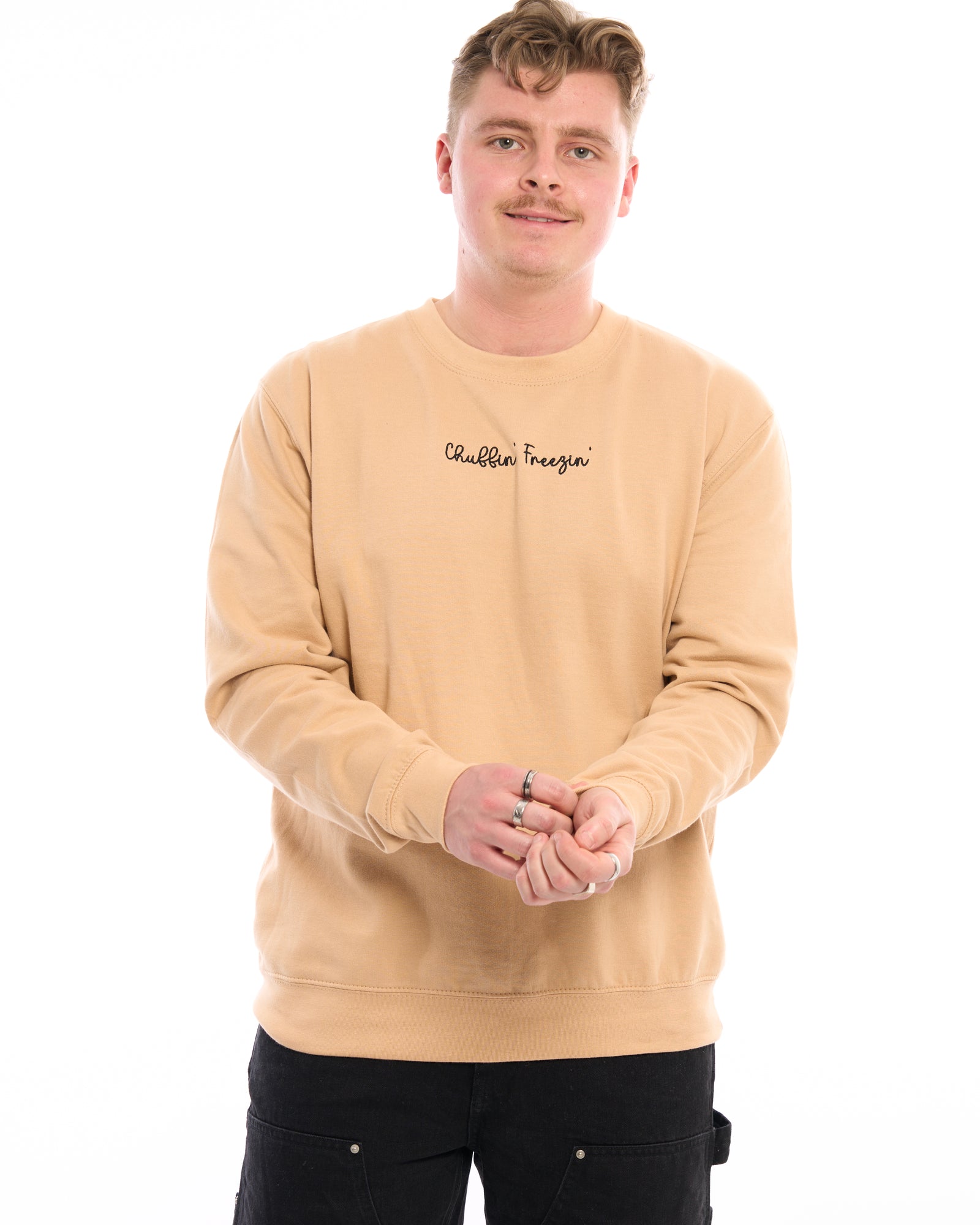 Woman wearing a dusty pink sweatshirt with “Chuffin’ Freezin’” embroidered.