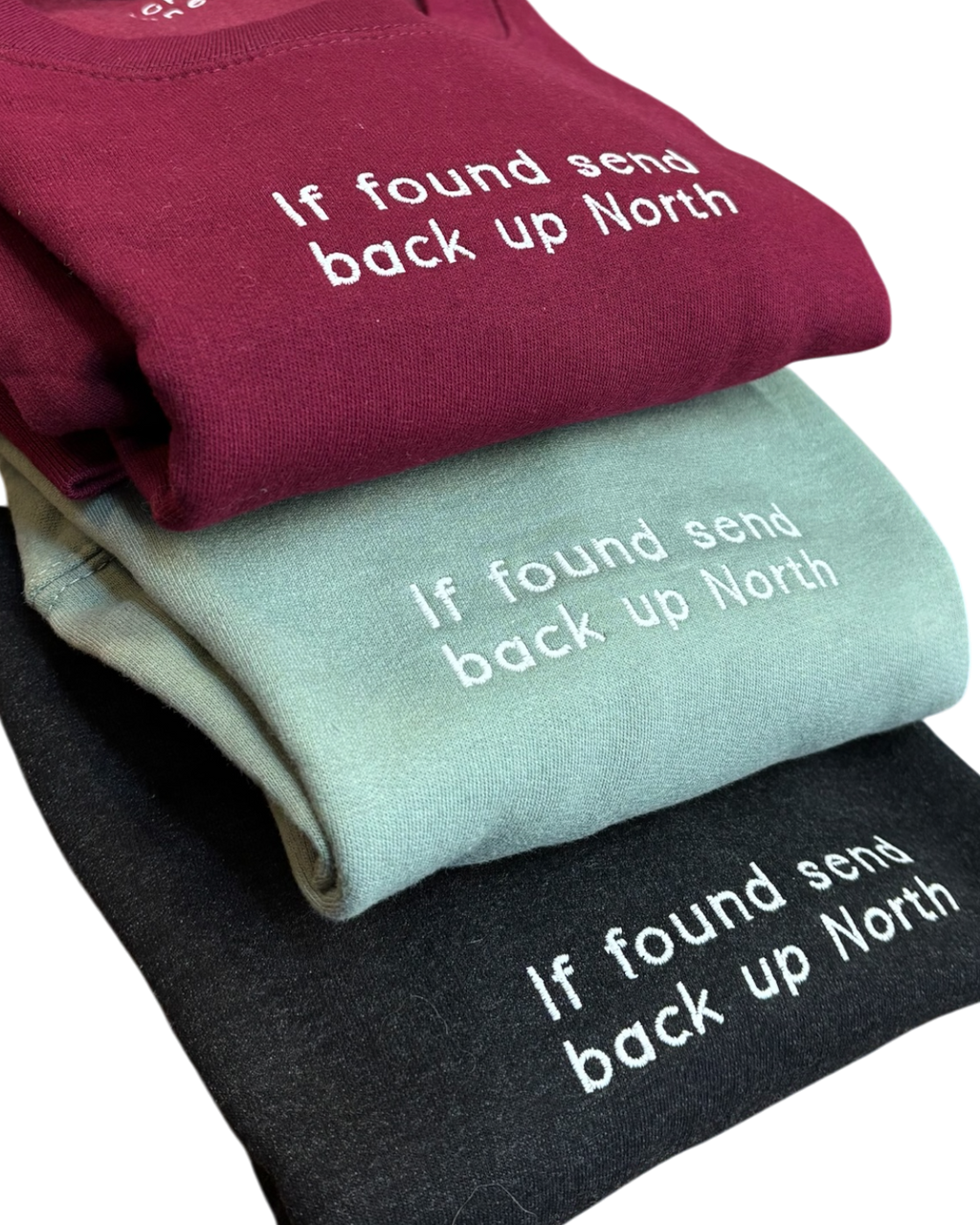 LighthouseLane unisex sweatshirts in burgundy, sage green, and black with white embroidered If Found Up North slogan