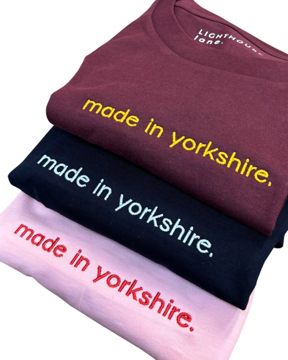 LighthouseLane organic cotton t-shirts in burgundy, navy, and pink with embroidered Made in Yorkshire slogan.