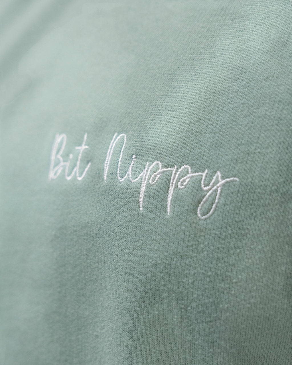 LighthouseLane sage green cotton blend sweatshirt featuring white Bit Nippy cursive embroidery on the chest