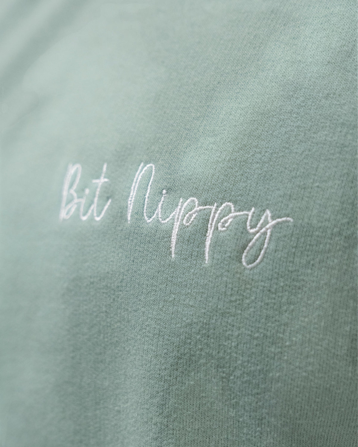 LighthouseLane sage green cotton blend sweatshirt featuring white Bit Nippy cursive embroidery on the chest