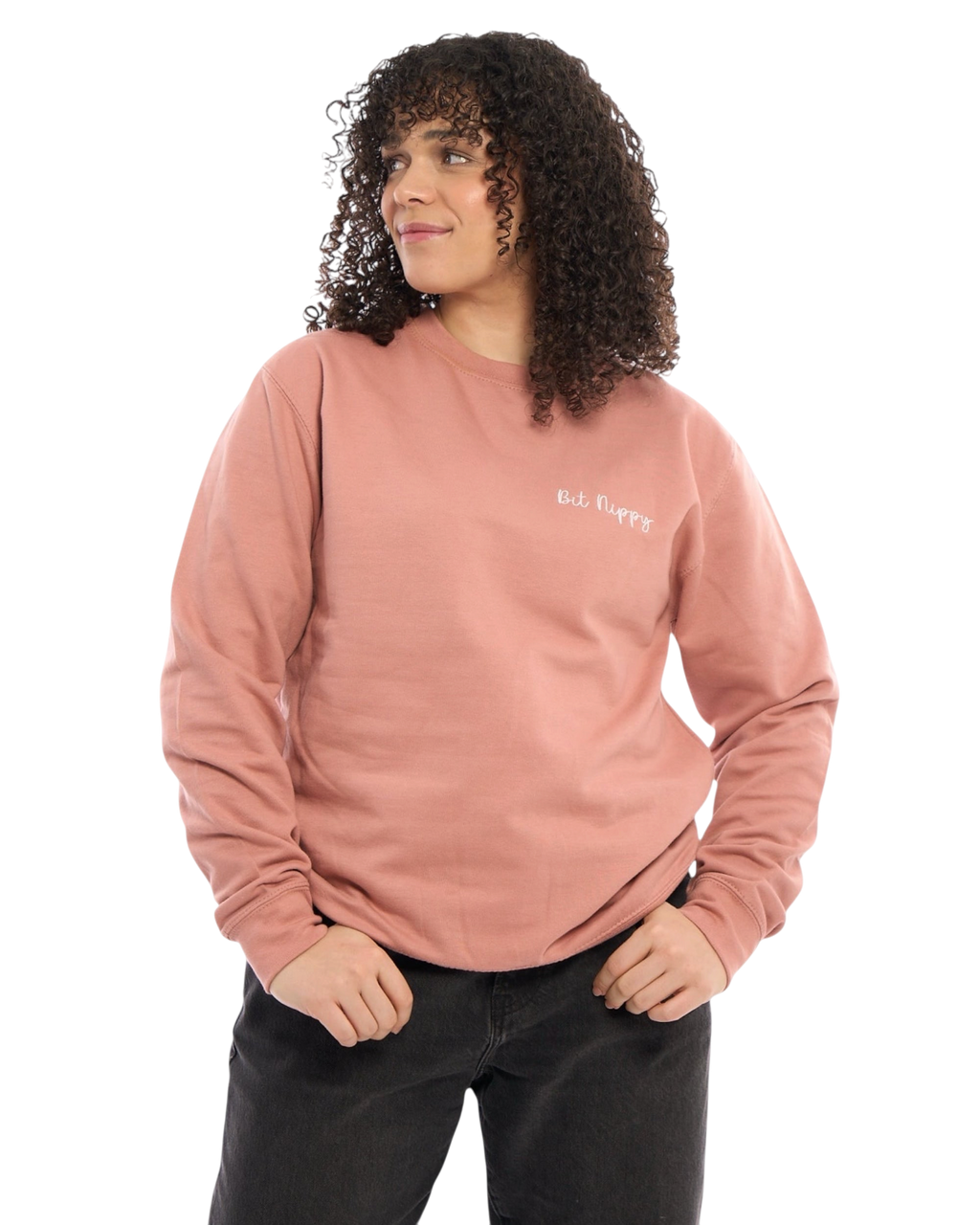 LighthouseLane unisex dusty pink sweatshirt with Bit Nippy slogan embroidery, worn by a woman with curly hair.