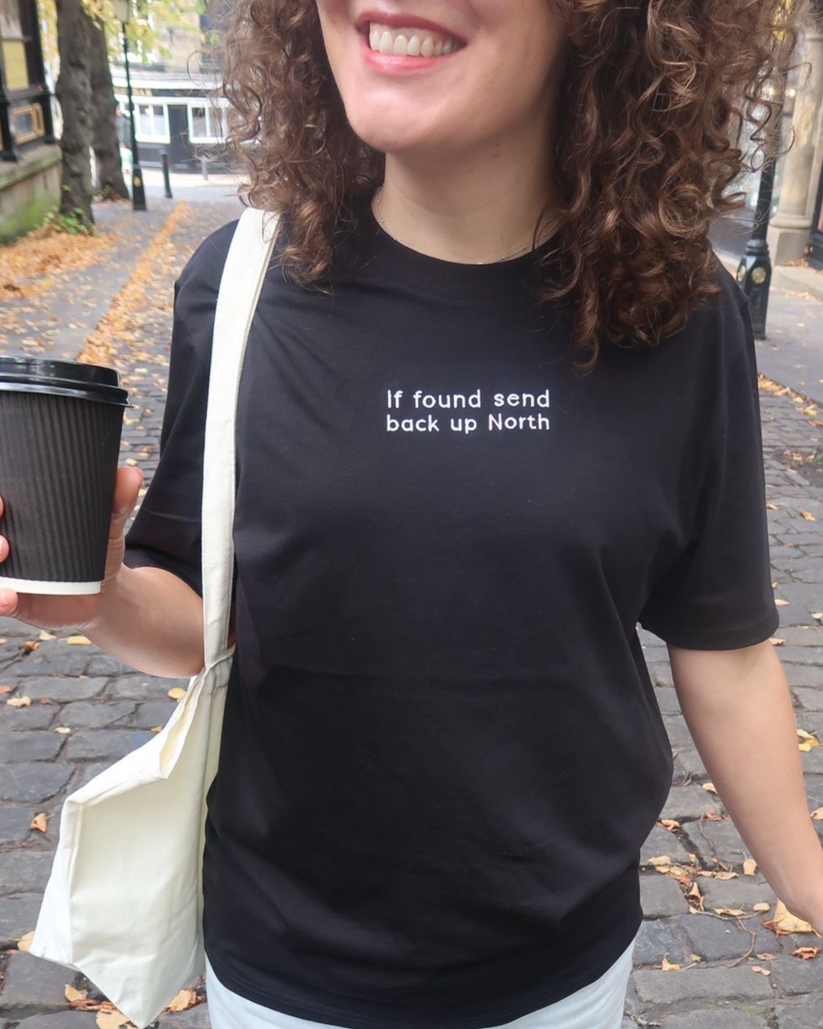 LighthouseLane black organic cotton unisex t-shirt with If Found Send Up North slogan embroidery on a woman
