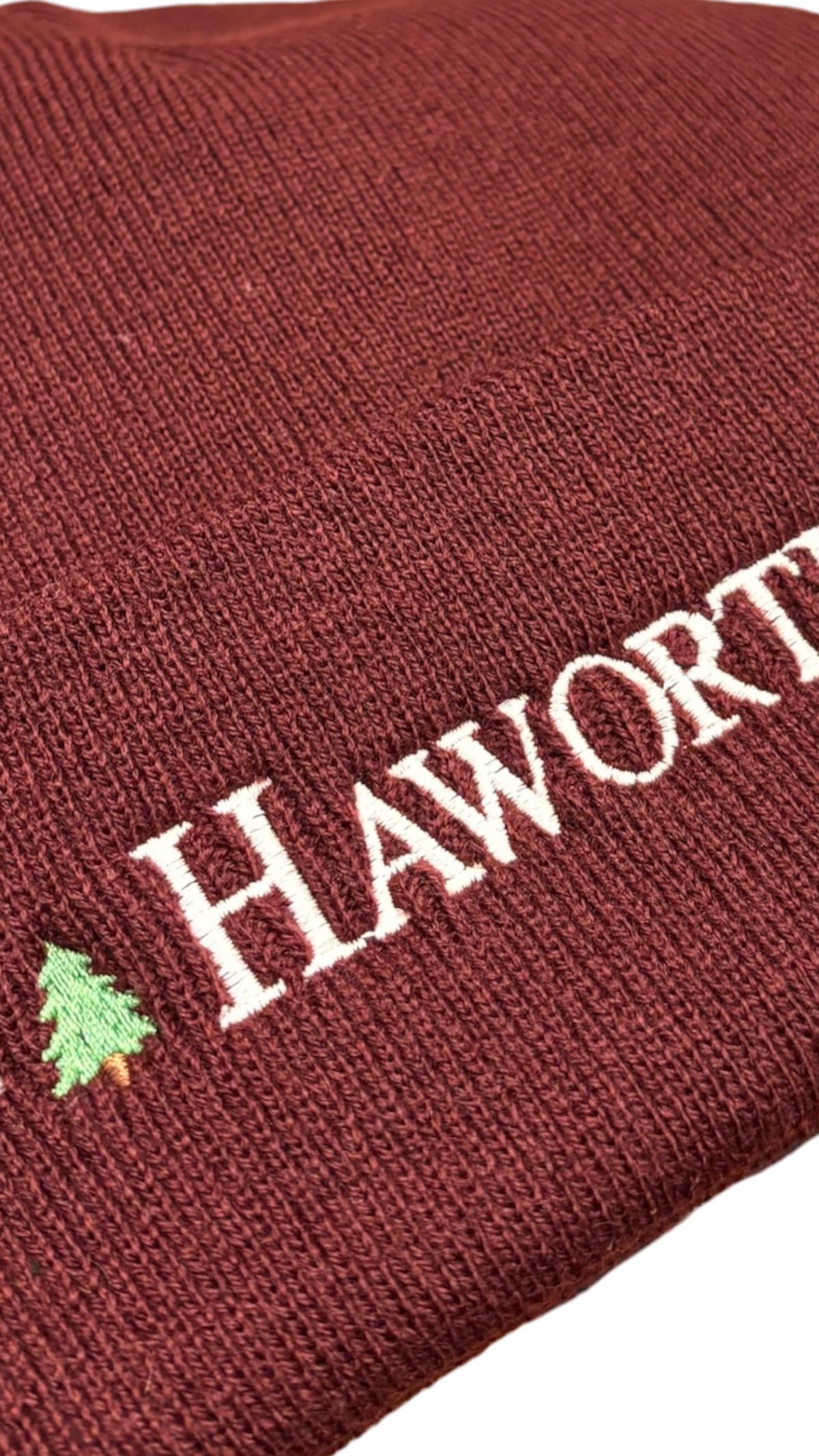 LighthouseLane burgundy acrylic beanie with white Haworth embroidery and a small green Christmas tree detail