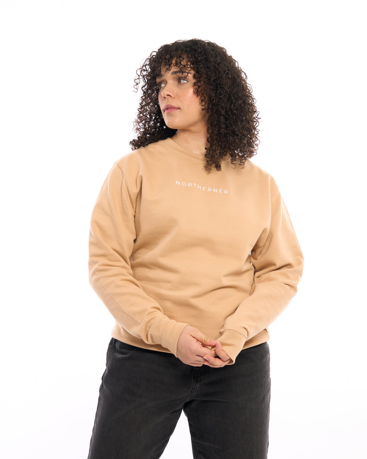LighthouseLane Northerner embroidered beige unisex sweatshirt worn by a woman with curly hair on a white background