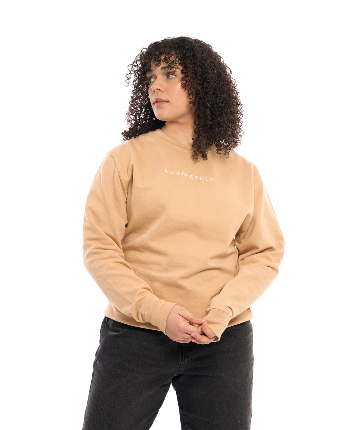 LighthouseLane Northerner embroidered beige unisex sweatshirt worn by a woman with curly hair on a white background