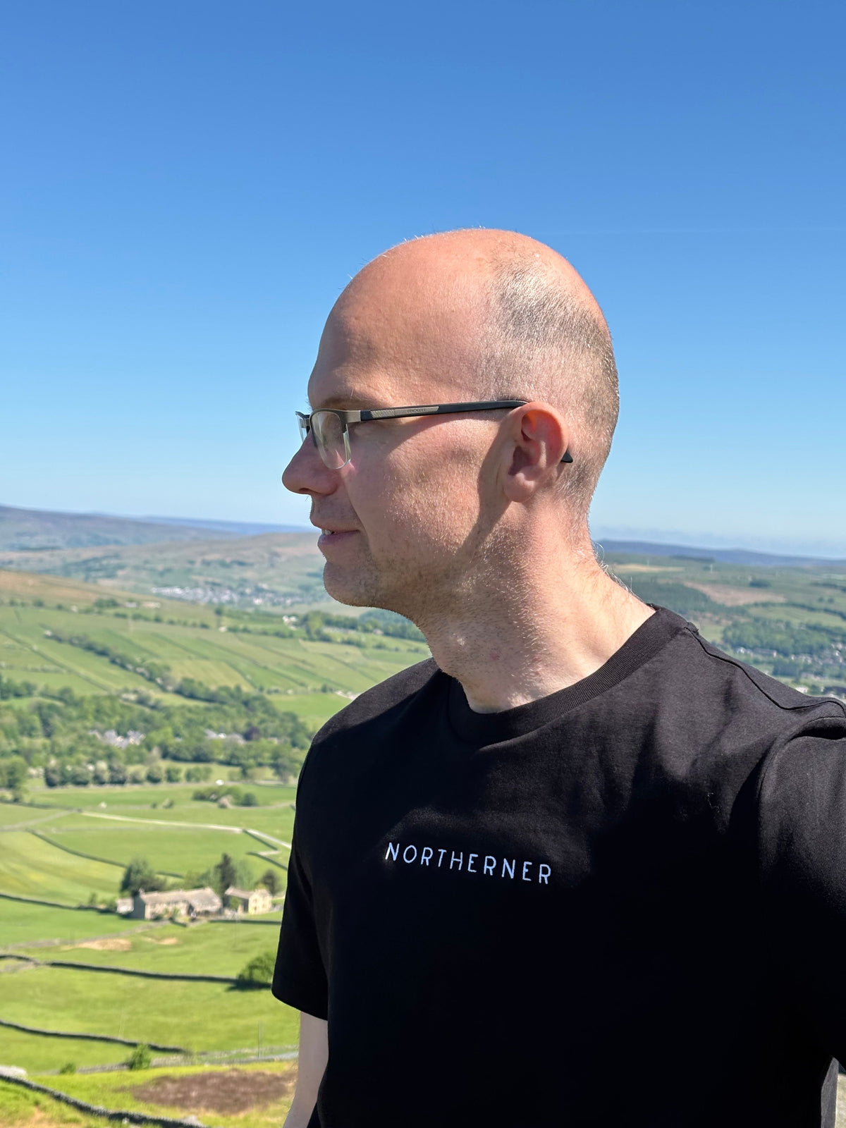 LighthouseLane Northerner black organic cotton t-shirt with white embroidery worn by a man in a scenic landscape