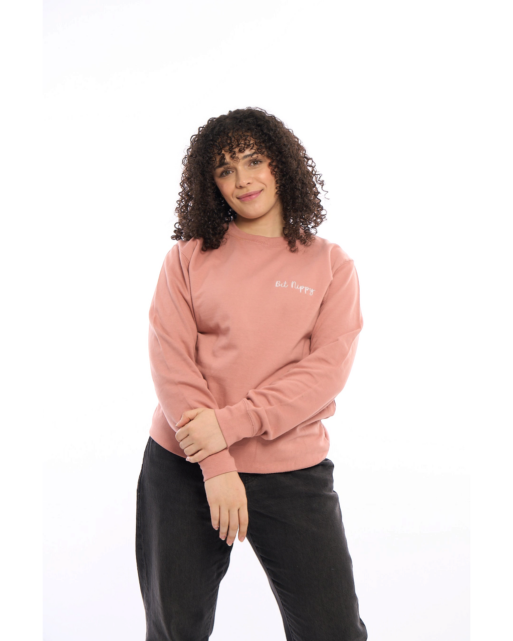LighthouseLane unisex pink sweatshirt with Bit Nippy embroidery worn by a woman with curly hair against white background