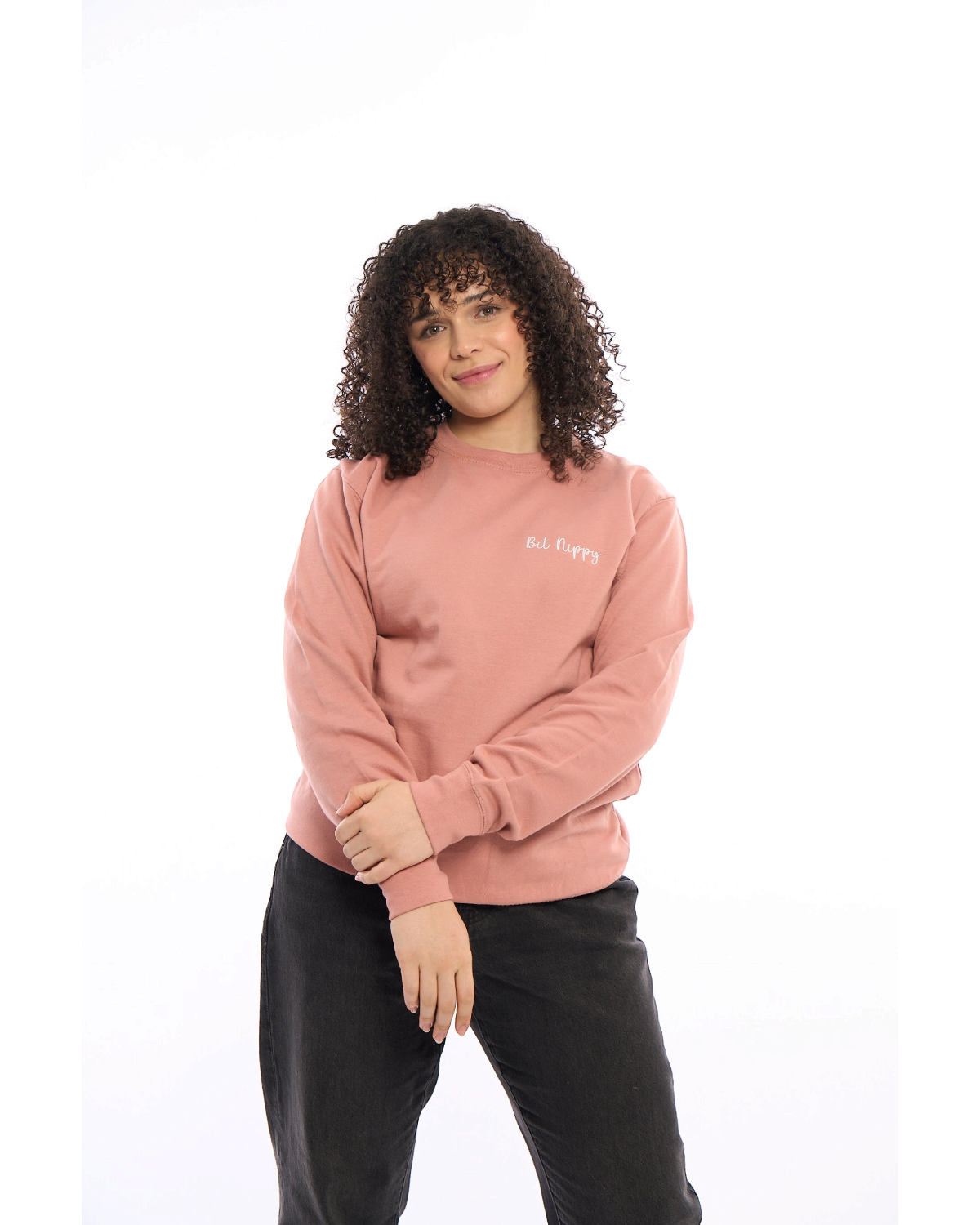 LighthouseLane unisex pink sweatshirt with Bit Nippy embroidery worn by a woman with curly hair against white background