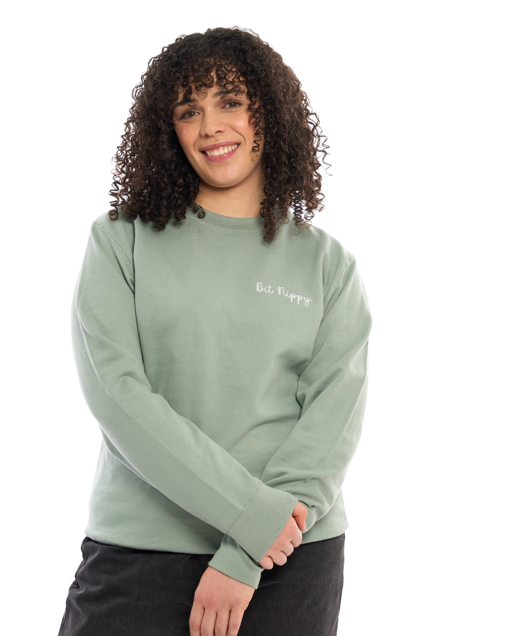 LighthouseLane sage green unisex sweatshirt with Bit Nippy embroidery worn by a woman with curly hair