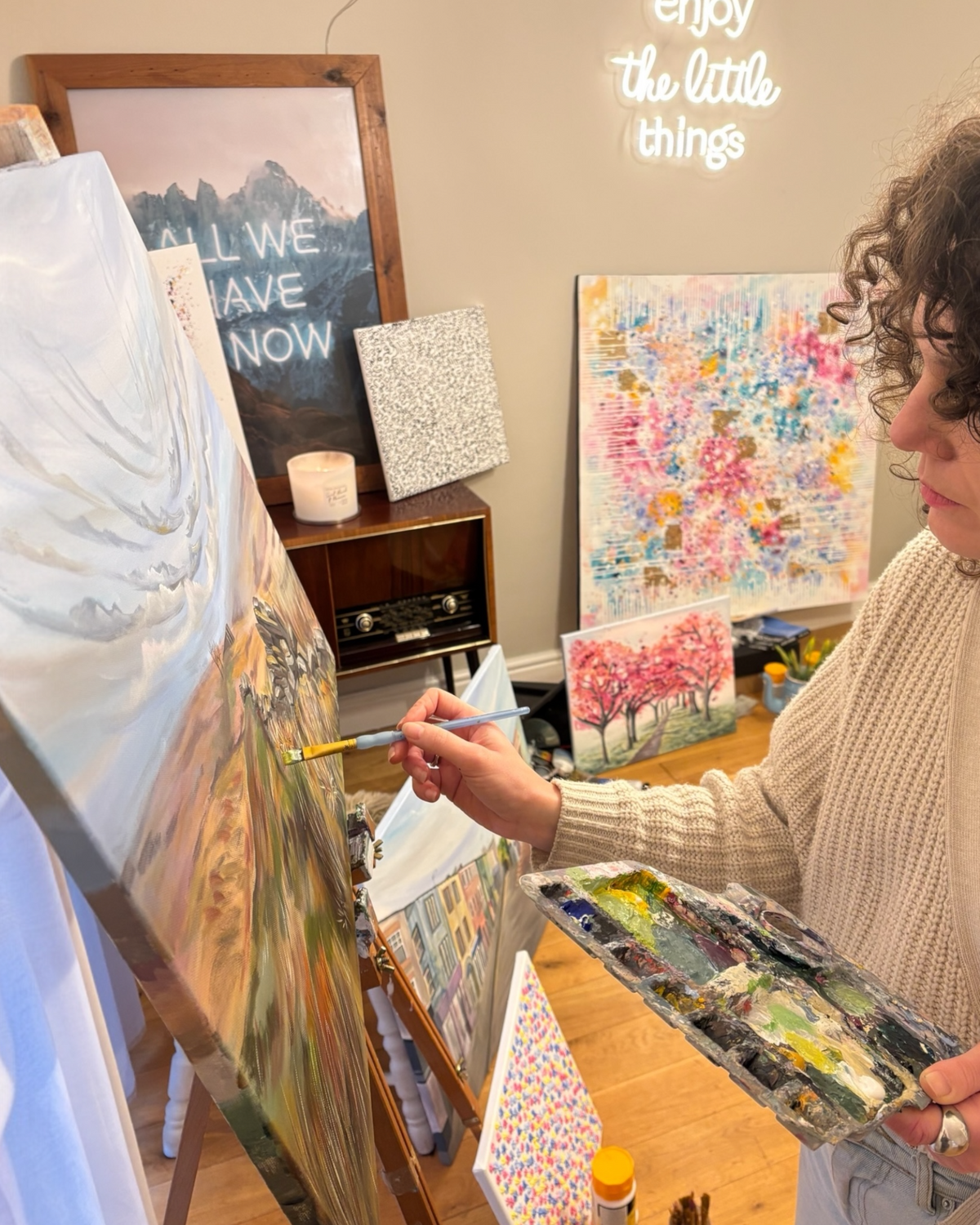 LighthouseLane artist painting a landscape of Top Withens on canvas in a bright studio with other artworks