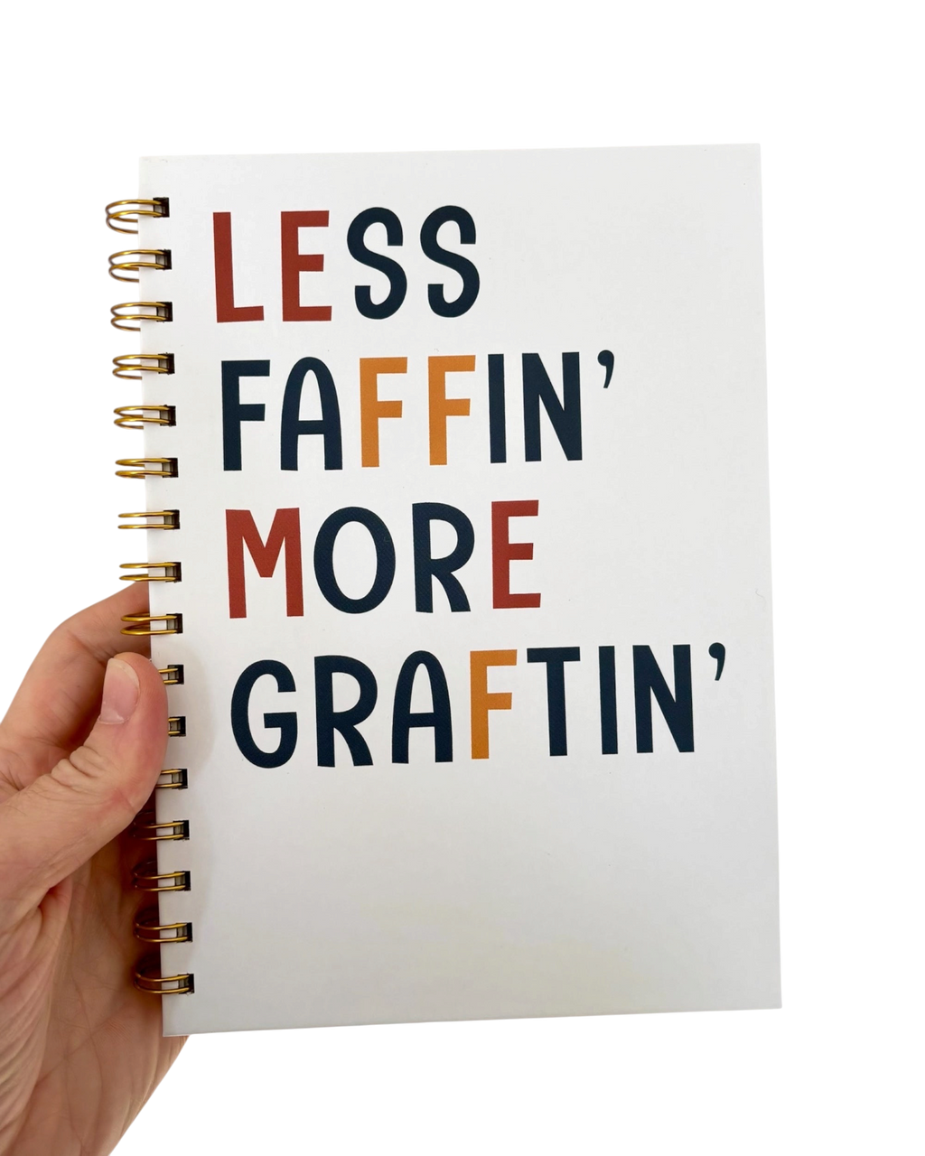 LighthouseLane A5 hardback notebook with Less Faffin More Graftin text and gold spiral binding held in a hand