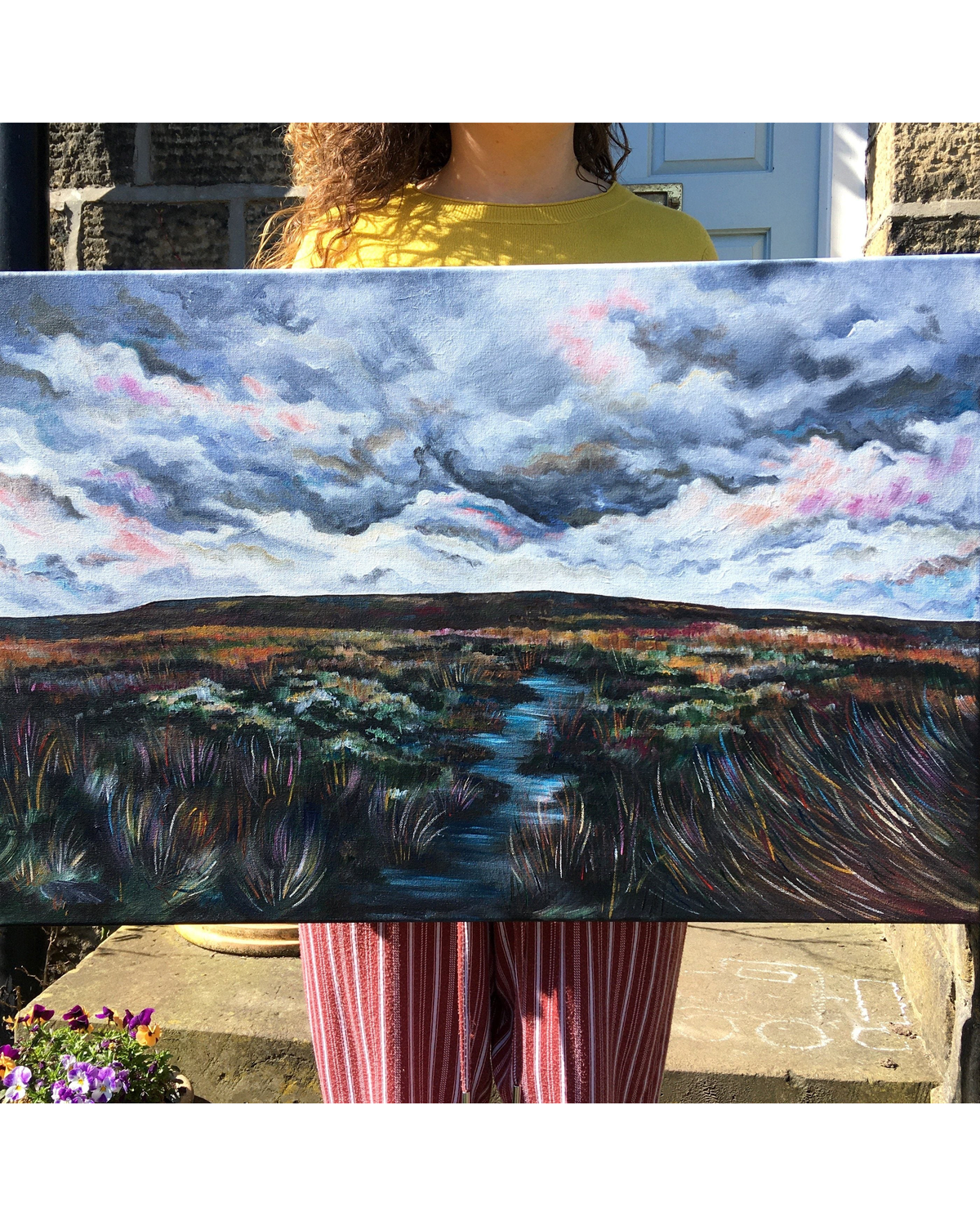 LighthouseLane Yorkshire moorland painting with a stormy sky, held by a person outdoors in natural light.